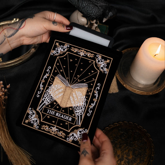 Person holding a kindle pouch with a candle and broomstick on a dark background