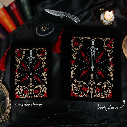 Black pouches with decorative designs featuring a sword and red flowers, labeled 'e-reader sleeve' and 'book sleeve'.