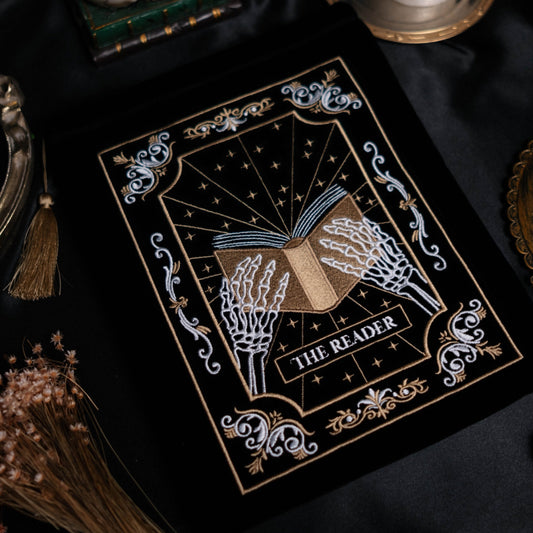 Decorative kindle pouch titled 'The Reader' with a candle and skull on a dark background