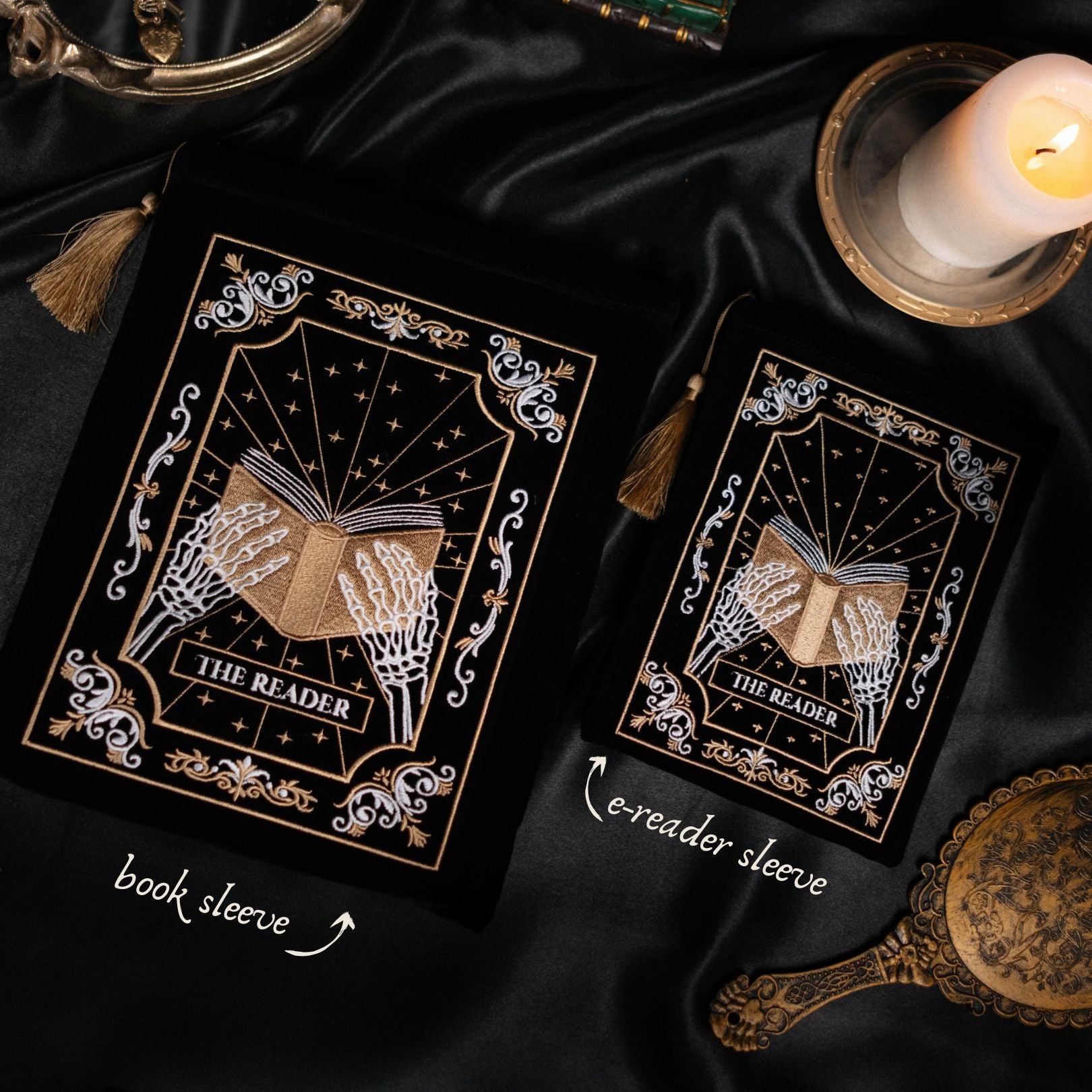 Two book sleeves with decorative designs on a dark fabric background with a candle.