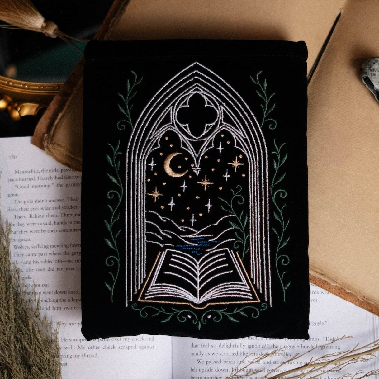 Decorative setup with a black kindle pouch, notebook, and black book on a dark background